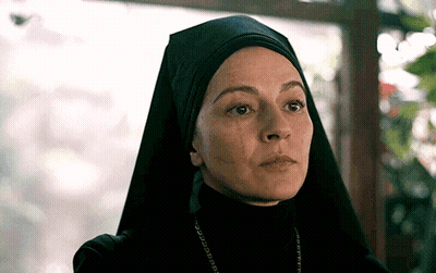A Close Up Of A Woman Wearing A Black Veil And A Necklace GIF