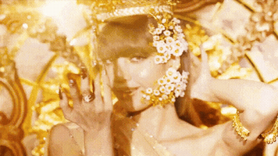 A Close Up Of A Woman Wearing A Crown And Earrings With Flowers On Her Face . GIF