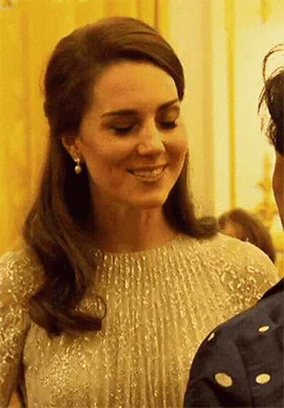 A Close Up Of A Woman Wearing A Dress And Earrings Smiling . GIF