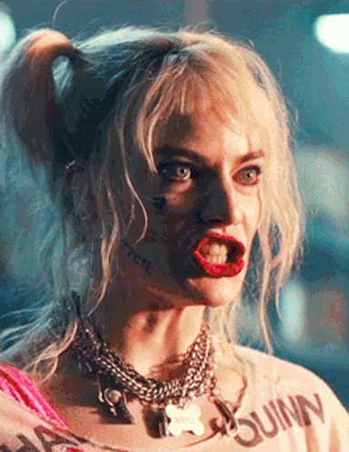 A Close Up Of A Woman Wearing A Harley Quinn Shirt And Necklace . GIF