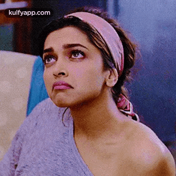 A Close Up Of A Woman Wearing A Headband And A Sweater Looking Up . GIF