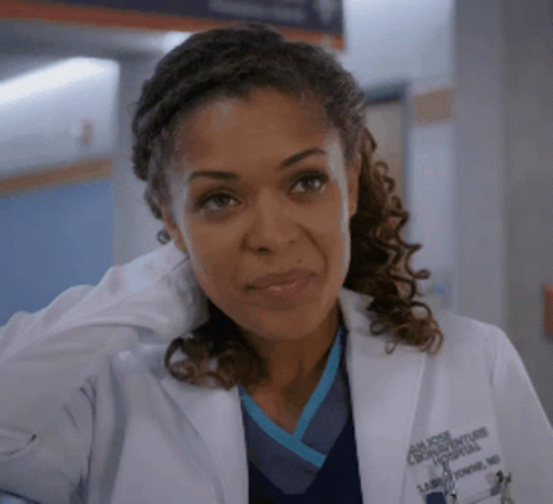 A Close Up Of A Woman Wearing A Lab Coat And Scrubs GIF