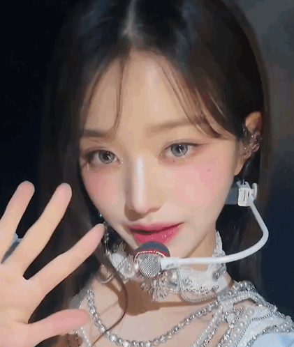 A Close Up Of A Woman Wearing A Microphone And Pearls GIF