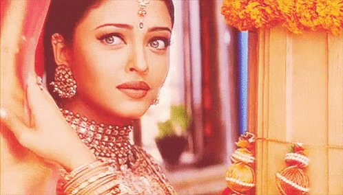 A Close Up Of A Woman Wearing A Necklace And Earrings Standing Next To A Window . GIF