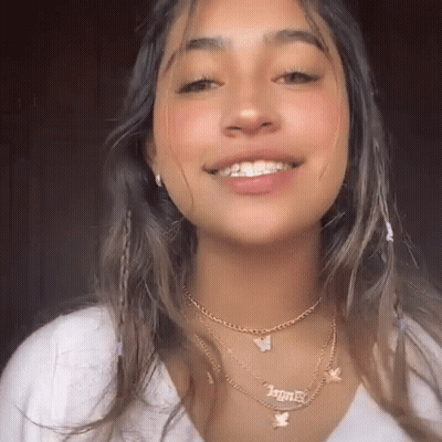 A Close Up Of A Woman Wearing A Necklace With A Butterfly Pendant . GIF