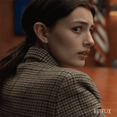 A Close Up Of A Woman Wearing A Plaid Jacket And Earrings . GIF