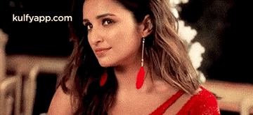 A Close Up Of A Woman Wearing A Red Dress And Earrings . GIF