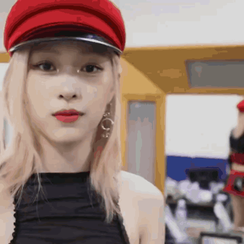 A Close Up Of A Woman Wearing A Red Hat And Earrings GIF