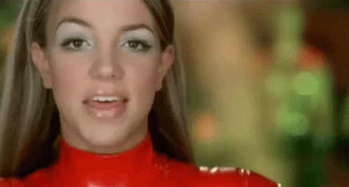 A Close Up Of A Woman Wearing A Red Latex Outfit And White Eye Shadow . GIF