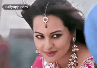 A Close Up Of A Woman Wearing A Saree And Earrings . GIF