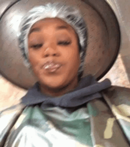 A Close Up Of A Woman Wearing A Shower Cap And A Hat . GIF