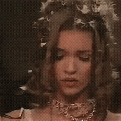 a close up of a woman wearing a veil and a necklace with flowers in her hair .