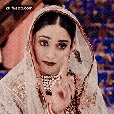 A Close Up Of A Woman Wearing A Veil And A Necklace . GIF