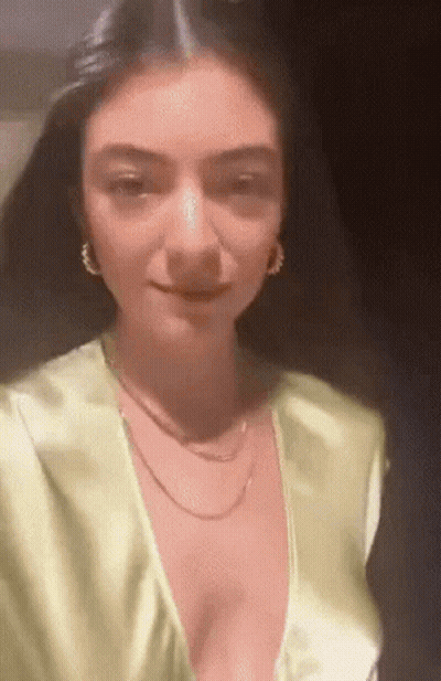 A Close Up Of A Woman Wearing A Very Plunging Neckline And Earrings . GIF