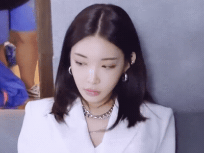 A Close Up Of A Woman Wearing A White Jacket And A Silver Necklace GIF