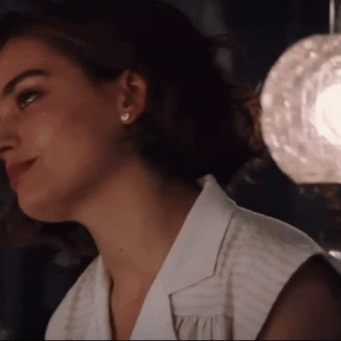 A Close Up Of A Woman Wearing A White Shirt And Earrings GIF