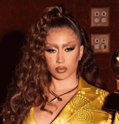 A Close Up Of A Woman Wearing A Yellow Dress And A Gold Necklace Holding A Trophy . GIF