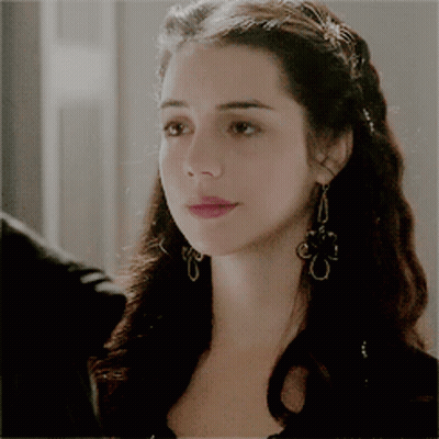 A Close Up Of A Woman Wearing Earrings And A Braided Hairstyle GIF
