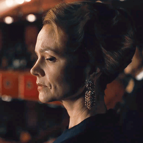 A Close Up Of A Woman Wearing Earrings And A Bun GIF
