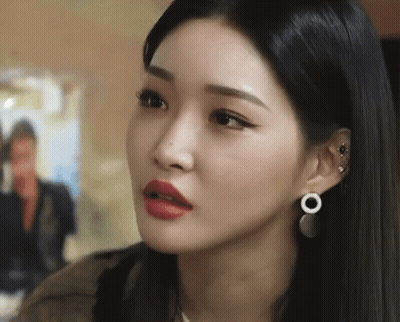 A Close Up Of A Woman Wearing Earrings And Red Lipstick Making A Funny Face . GIF