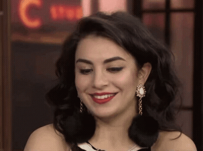 A Close Up Of A Woman Wearing Earrings And Red Lipstick Smiling . GIF