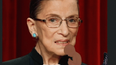 A Close Up Of A Woman Wearing Glasses And A Black Suit GIF