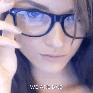 A Close Up Of A Woman Wearing Glasses With The Words `` We Are Bad '' Written On The Bottom . GIF