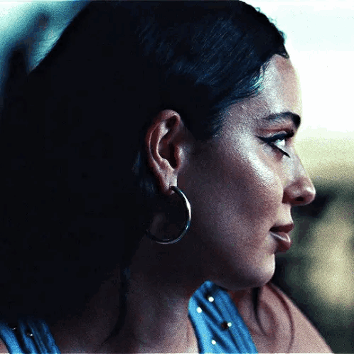 A Close Up Of A Woman Wearing Hoop Earrings And A Blue Shirt . GIF