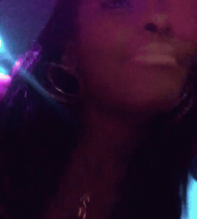 A Close Up Of A Woman Wearing Hoop Earrings And A Necklace With The Letter C On It GIF