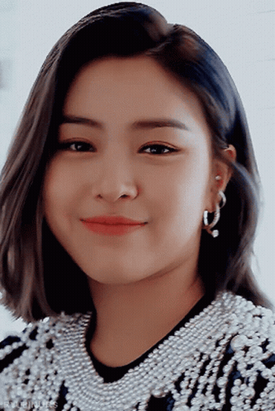 A Close Up Of A Woman Wearing Hoop Earrings And A Sweater With Pearls GIF