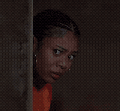 A Close Up Of A Woman Wearing Hoop Earrings And An Orange Shirt GIF