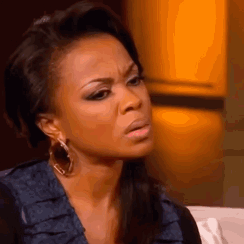 A Close Up Of A Woman Wearing Hoop Earrings Making A Funny Face GIF
