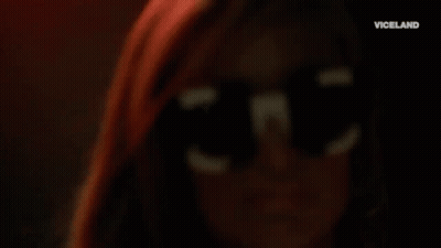 A Close Up Of A Woman Wearing Sunglasses And Hoop Earrings . GIF