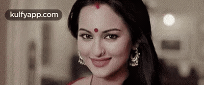 A Close Up Of A Woman With A Red Dot On Her Forehead Smiling . GIF