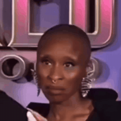A Close Up Of A Woman With A Shaved Head And Earrings Making A Funny Face . GIF