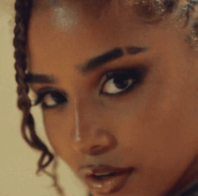 A Close Up Of A Woman With Braids And Hoop Earrings GIF