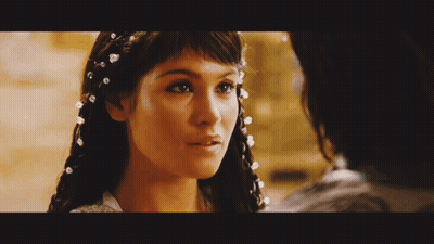 A Close Up Of A Woman With Pearls In Her Hair Looking At A Man GIF