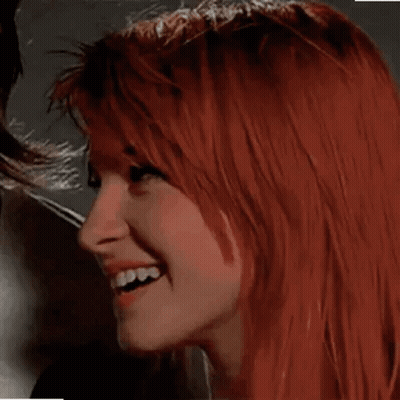 A Close Up Of A Woman With Red Hair Smiling And Looking At The Camera . GIF