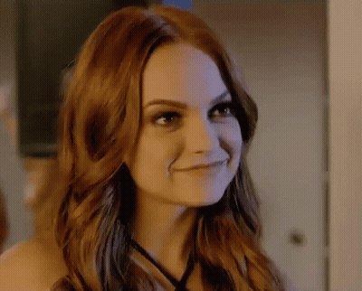 A Close Up Of A Woman With Red Hair Smiling In A Room . GIF