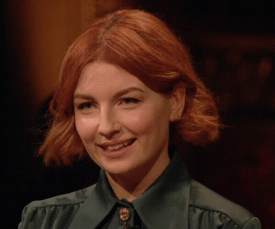 A Close Up Of A Woman With Red Hair Wearing A Green Shirt . GIF