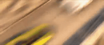 A Close Up Of A Yellow Car Driving Down A Wooden Road . GIF
