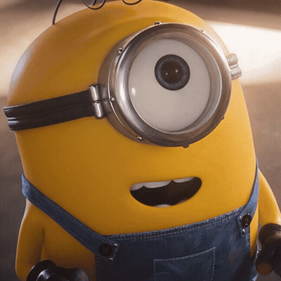 A Close Up Of A Yellow Minion Wearing Overalls GIF