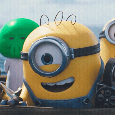 A Close Up Of A Yellow Minion Wearing Overalls GIF