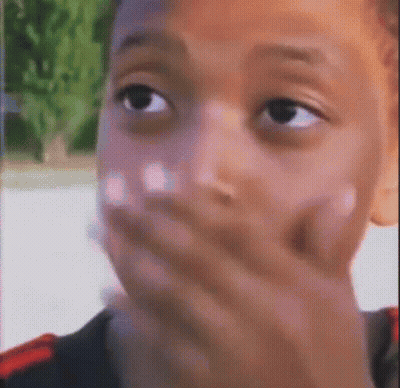 A Close Up Of A Young Boy Covering His Mouth With His Hand . GIF