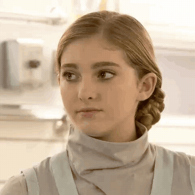 A Close Up Of A Young Girl Wearing A Turtleneck Sweater And An Apron . GIF
