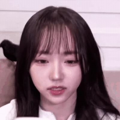 A Close Up Of A Young Girl With Long Hair And Bangs Looking At The Camera . GIF