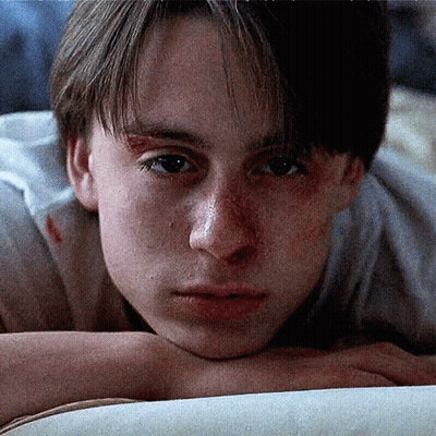 A Close Up Of A Young Man Laying On A Bed GIF