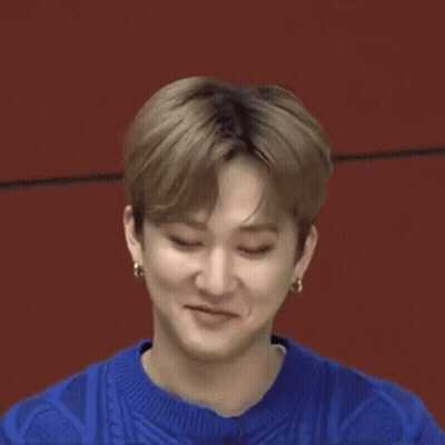 A Close Up Of A Young Man Making A Funny Face While Wearing A Blue Sweater And Earrings . GIF