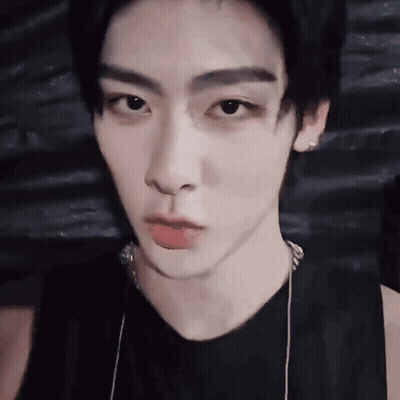 A Close Up Of A Young Man 'S Face Wearing A Black Tank Top And Necklace . GIF