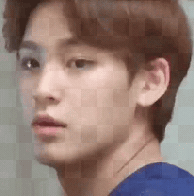 A Close Up Of A Young Man 'S Face Wearing A Blue Shirt And Looking At The Camera . GIF